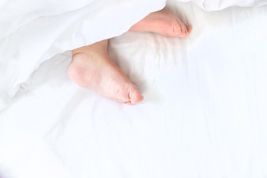 Baby sleeps on a white bed with his feet. Selective focus. Child.