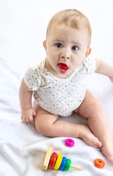 Baby takes the toy into her mouth. Selective focus. People.