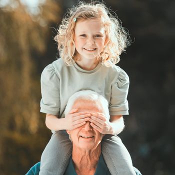 Shot of a girl being carried by her grandfather outside.