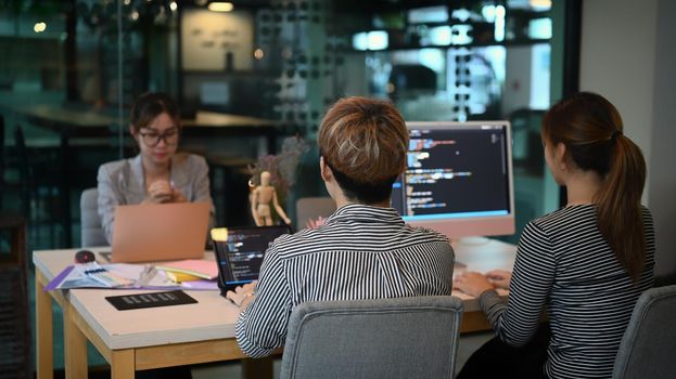 Software developers team brainstorming and programming in co working space.