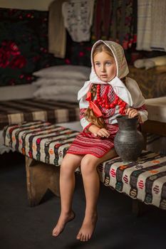girl in Ukrainian national costume sits on a bench in the house