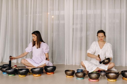 Two female yoga teachers play on Tibetan bowls in the gym during a yoga retreat.