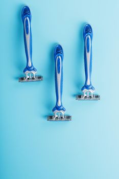 Three shaving machines on a blue background with free space, top view