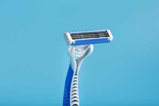 Blue shaving machine with sharp blades on the background of ice cubes close-up. The concept of cleanliness and frosty freshness