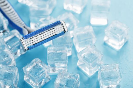 Shaving machine on a blue background with ice cubes. The concept of cleanliness and frosty freshness