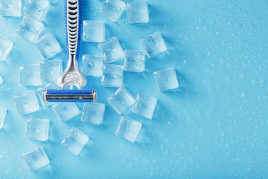 Shaving machine on a blue background with ice cubes. The concept of cleanliness and frosty freshness