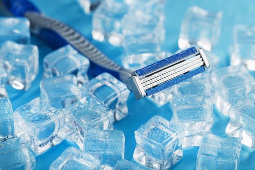 Shaving machine on a blue background with ice cubes. The concept of cleanliness and frosty freshness