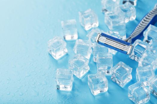 Shaving machine on a blue background with ice cubes. The concept of cleanliness and frosty freshness