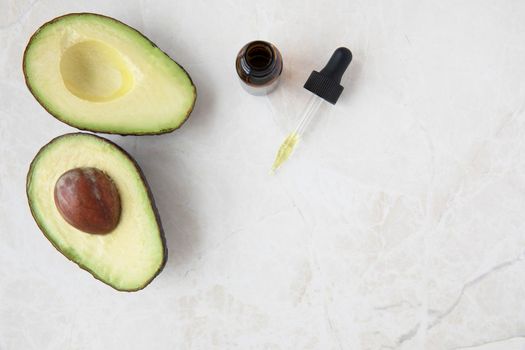 Avocados and avocado oil in dropper, flat lay with copy space