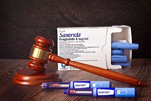 Judges hammer, Saxenda Injection pens on a wooden background. Injections for weight loss, lower blood sugar, and repels hunger. The concept for medical judgment. High quality photo