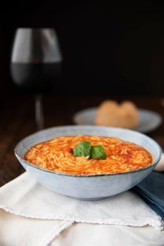 Bowl of orzo pasta and tomato soup with basil