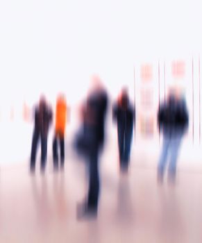Group of people in the lobby of a modern art center with a blurred background. Crowd of blurred people at exhibition or in a museum. People standing around inside a hall.