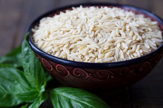 Bowl of orzo pasta with fresh basil leaves
