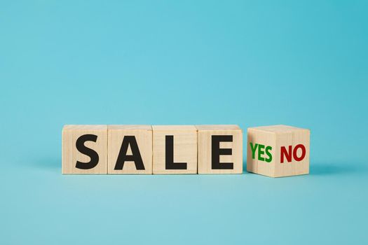 Sale word no to yes. Hand turns a dice and changes the word no to yes. On sale Cubes dice with Sale Yes or No on wooden background.