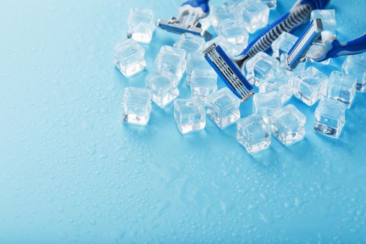 Shaving machine on a blue background with ice cubes. The concept of cleanliness and frosty freshness