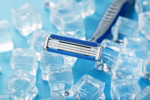 Blue shaving machines in a row on a blue background with ice cubes. The concept of cleanliness and frosty freshness