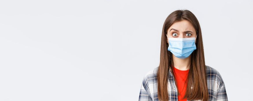 Coronavirus outbreak, leisure on quarantine, social distancing and emotions concept. Confused and startled girl in medical mask seeing something strange, raise eyebrow skeptical.