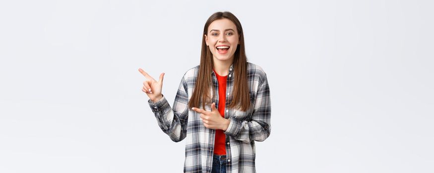 Lifestyle, different emotions, leisure activities concept. Enthusiastic beautiful young girl laughing carefree and pointing fingers upper left corner, showing way, recommend promo.