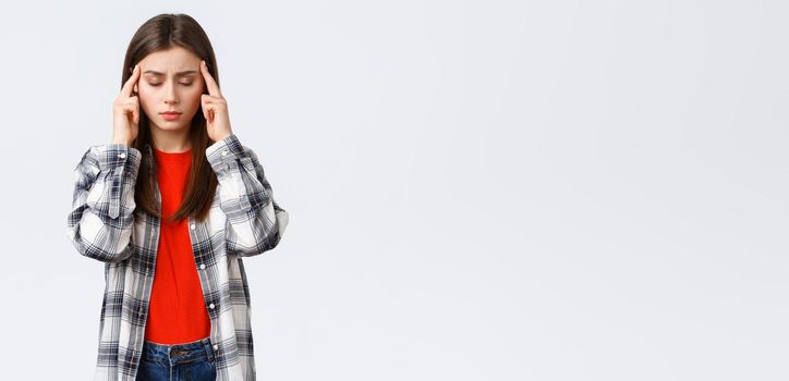 Lifestyle, different emotions, leisure activities concept. Distressed and exhausted young female student trying focus, feel headache or dizzy, close eyes and rub temples, white background.