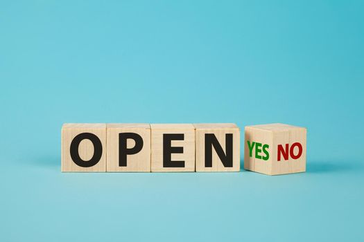 The word OPEN is written on wooden cubes. The hand turns the wooden cube and changes the word NO OPEN to YES OPEN.