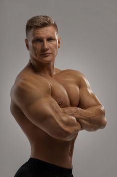 Professional bodybuilder in a dry filled form in a large weight category posing on a grey background. Sports lifestyle.