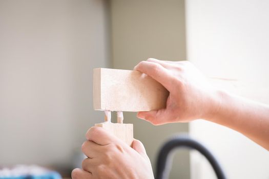 Woodworking operators are using glue to put together the wood parts to assemble and build a wooden table for their customers