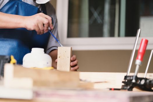 Woodworking operators are using glue to put together the wood parts to assemble and build a wooden table for their customers