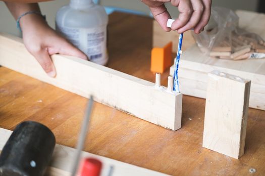 Woodworking operators are using glue to put together the wood parts to assemble and build a wooden table for their customers