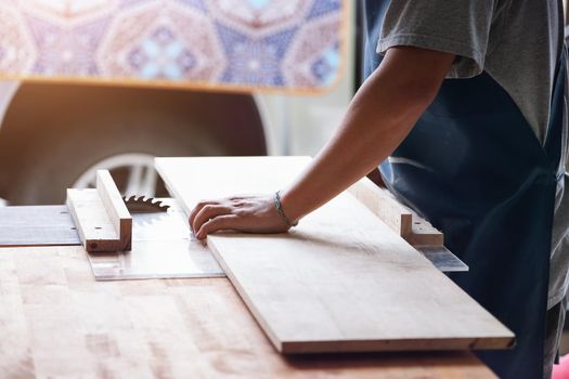 Woodworking operators are using plank cutting machines to assemble and build wooden tables for customers