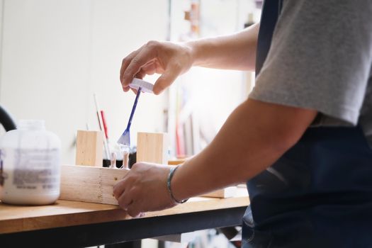 Woodworking operators are using glue to put together the wood parts to assemble and build a wooden table for their customers