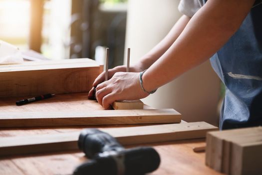 A carpenter measures the planks to assemble the parts, and build a wooden table for the customer