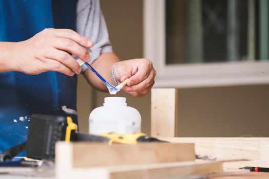 Woodworking operators are using glue to put together the wood parts to assemble and build a wooden table for their customers