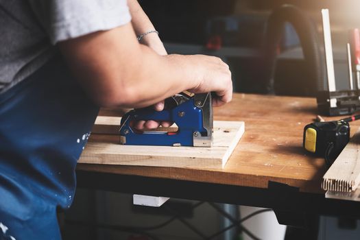 Entrepreneur Woodwork holding a Tacker to assemble the wood pieces as the customer ordered