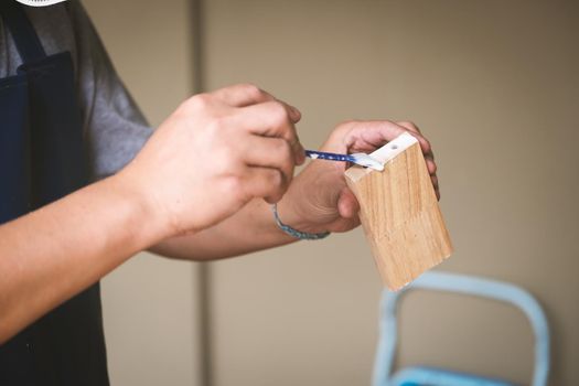 Woodworking operators are using glue to put together the wood parts to assemble and build a wooden table for their customers