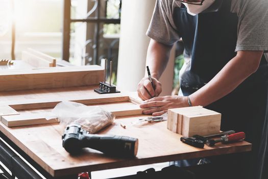 A carpenter measures the planks to assemble the parts, and build a wooden table for the customer