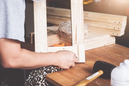 A carpenter measures the planks to assemble the parts, and build a wooden table for the customer