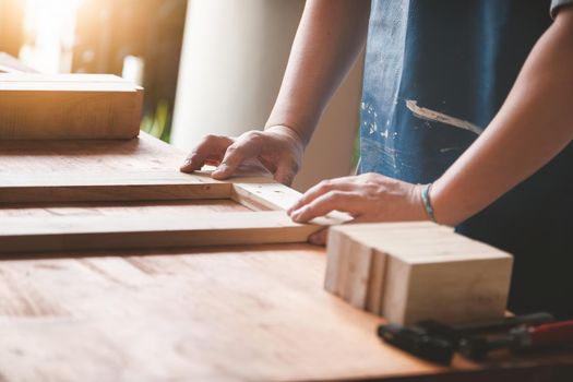 A carpenter measures the planks to assemble the parts, and build a wooden table for the customer