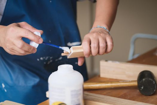 Woodworking operators are using glue to put together the wood parts to assemble and build a wooden table for their customers