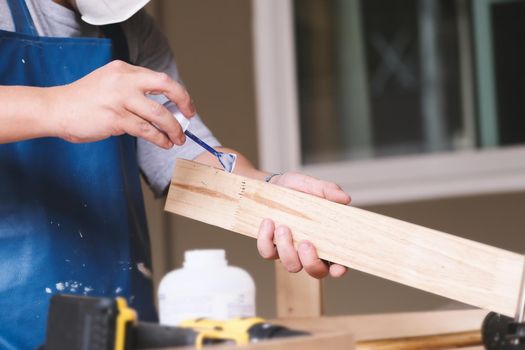 Woodworking operators are using glue to put together the wood parts to assemble and build a wooden table for their customers