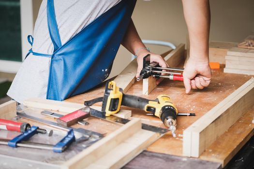 Woodworking operators are using woodworking tools to prepare a drill, drill holes in wood to assemble and build a wooden table for their customers