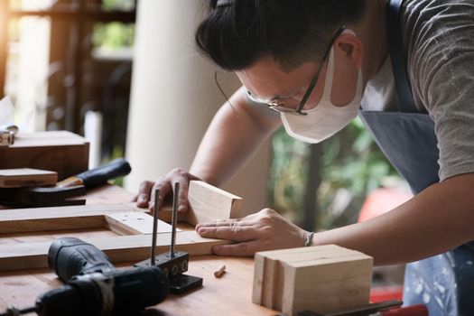 A carpenter measures the planks to assemble the parts and build a wooden table for the customer