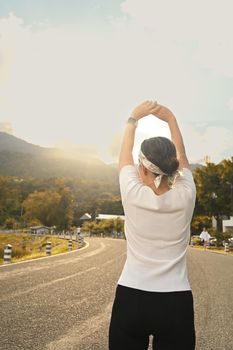 Back view of middle aged woman warming up before morning workout. Healthy lifestyle, workout and wellness concept.