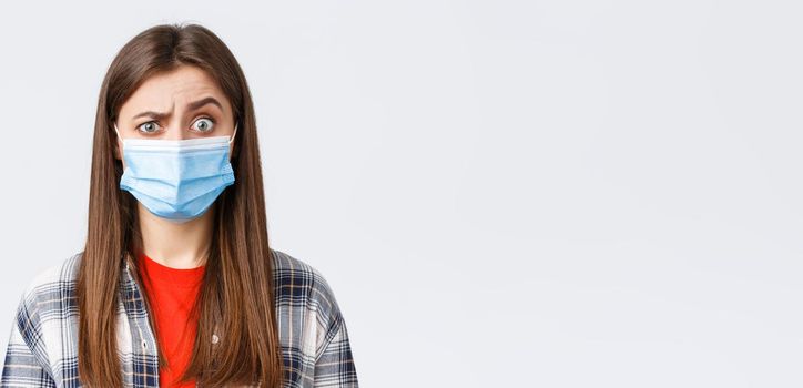 Coronavirus outbreak, leisure on quarantine, social distancing and emotions concept. Confused young woman cant understand what happening, look suspicious or surprised, wear medical mask.
