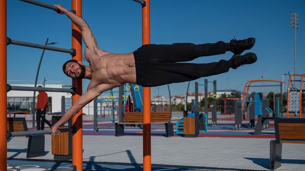 Shirtless man doing human flag outdoors