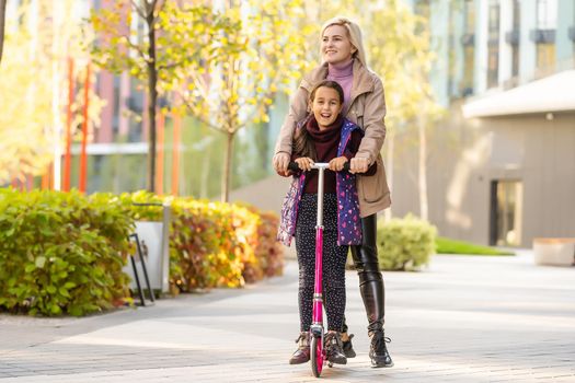 Mother Teaching Daughter To Ride Scooter.