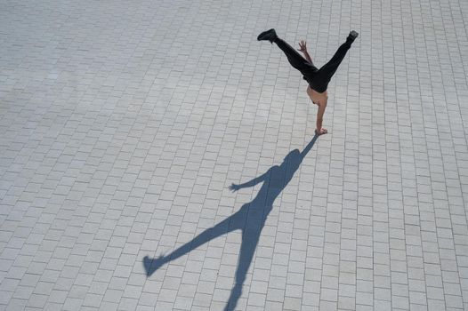 Shirtless man walks on his hands outdoors. View from above