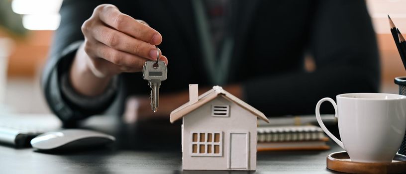 Cropped shot real estate agent holding house key. Insurance or loan real estate concept.