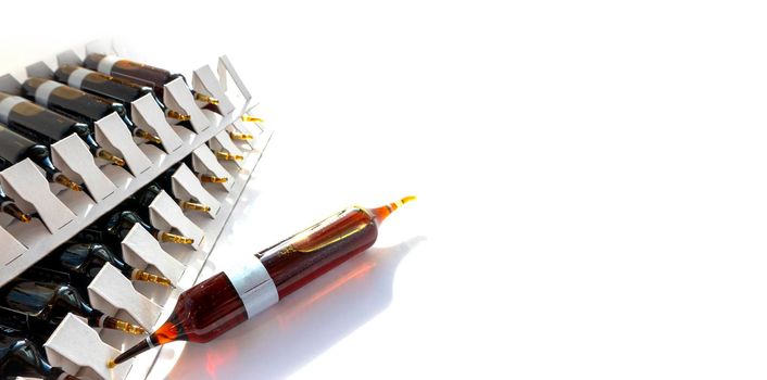 Group object of liquid medicinal agent in limpid glassware in medical laboratory. Group of ampoules with a transparent medicine in medical laboratory. horizontal perspective view of many brown ampoules set in pharmaceutical packaging white container