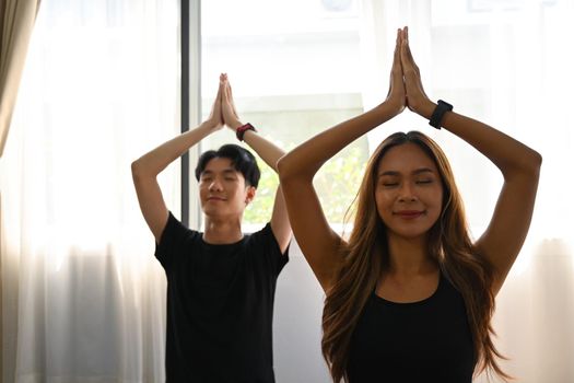 Asian young couple practicing yoga at home .Healthy lifestyle concept.