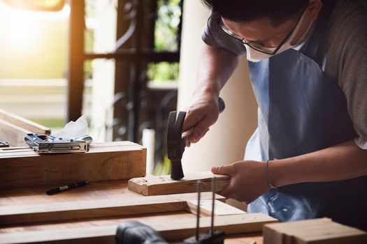 Entrepreneur Woodwork holding hammer to assemble the wood pieces as the customer ordered